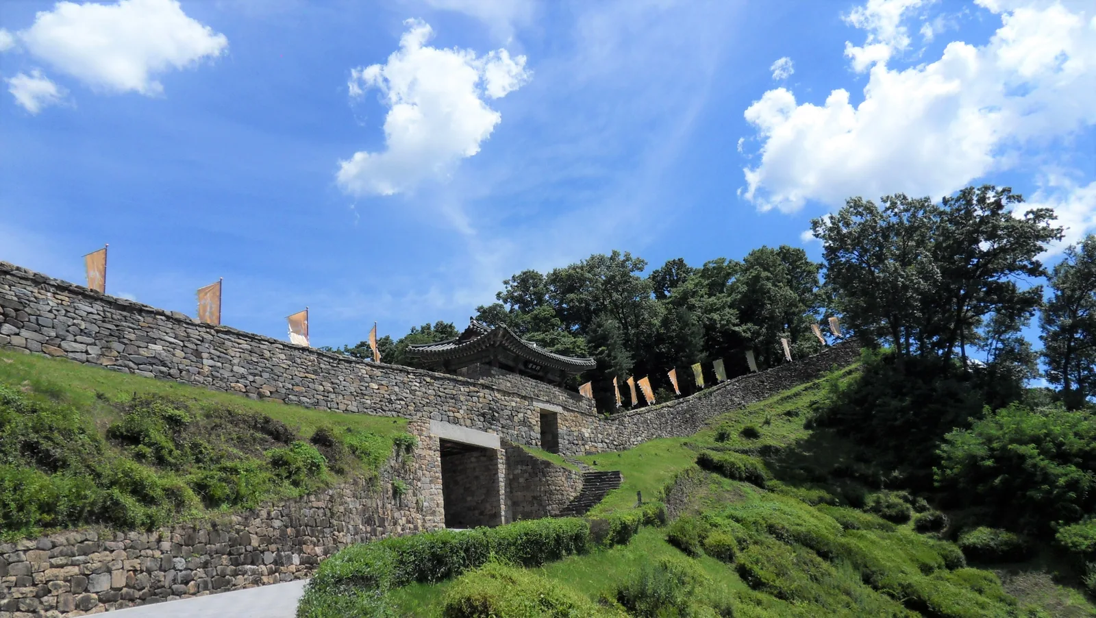 Stone fortress walls, a small arched passage and steep green earthworks inside Gongsanseong Fortress