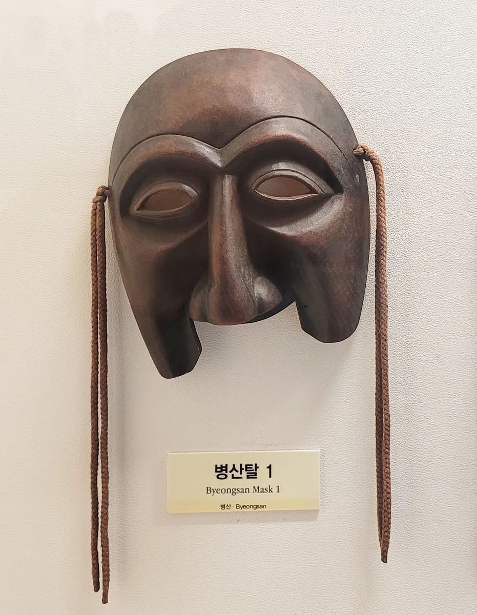A close view of a dark wooden Hahoe mask displayed inside Hahoe World Mask Museum