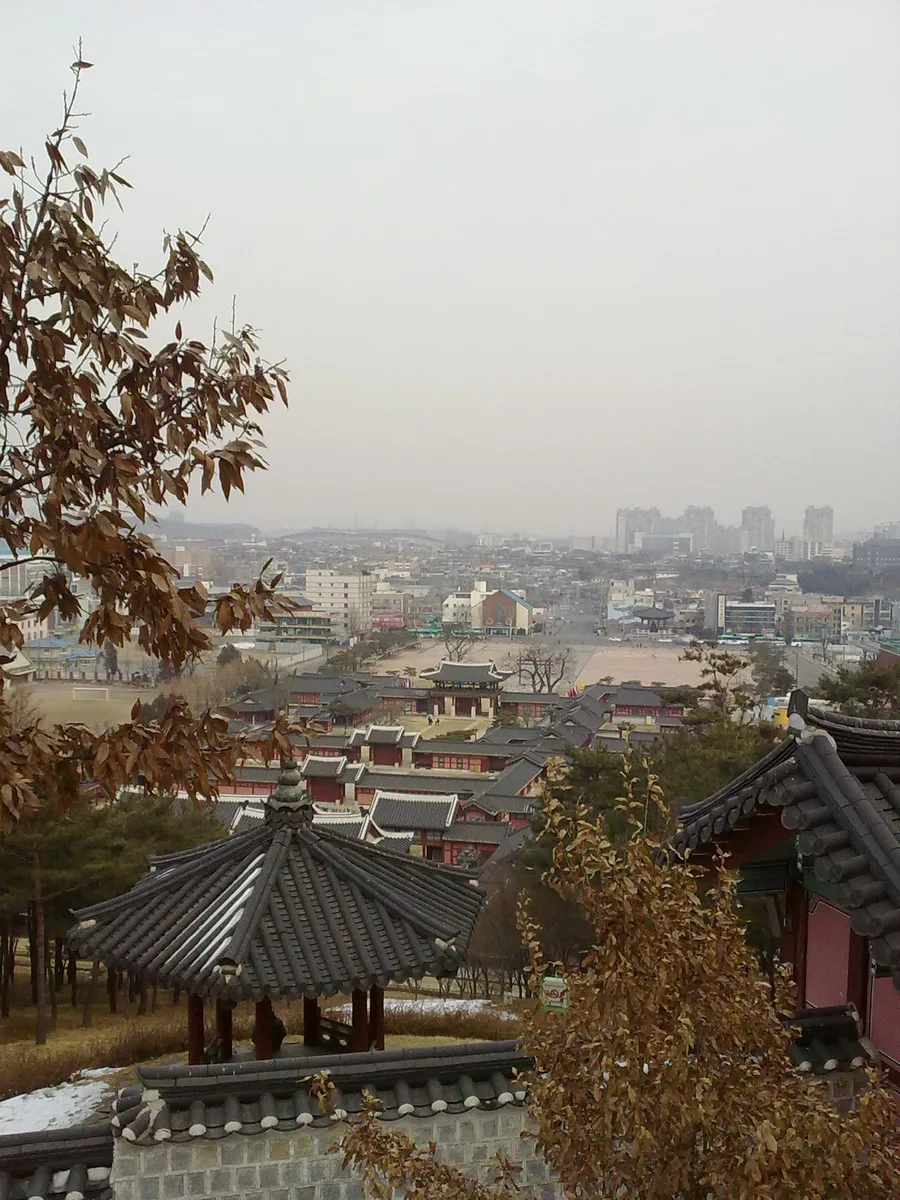 A real elevated view across Hwaseong Haenggung's tiled palace roofs and courtyards toward central Suwon