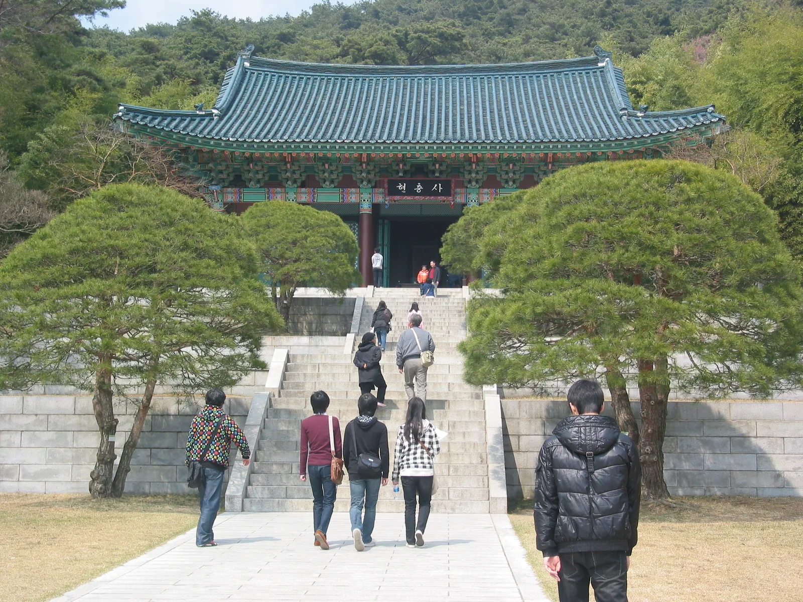 The tree-lined stone approach and main shrine building at Hyeonchungsa in Asan
