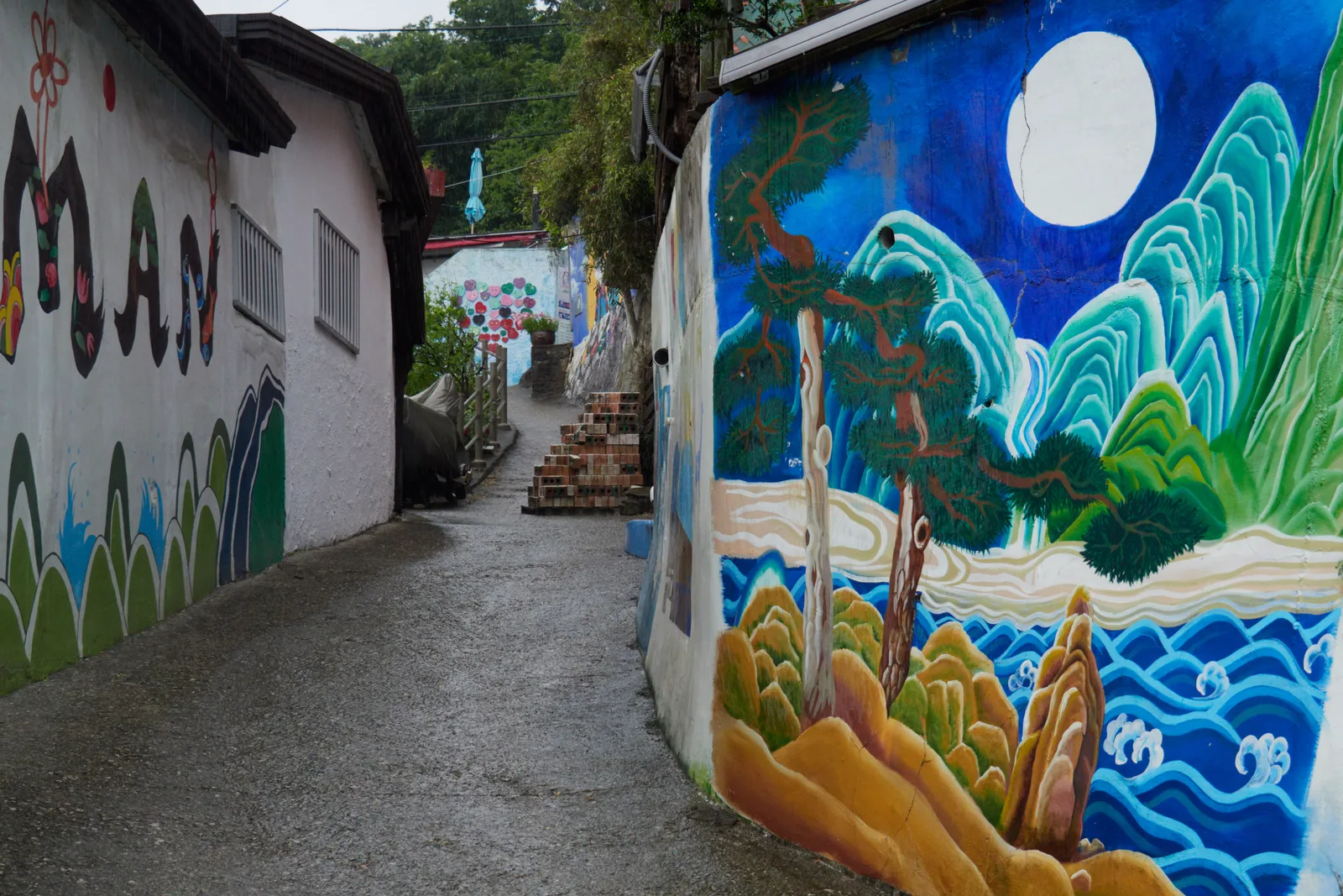 A narrow hillside stair lane between brightly painted mural walls in Jaman Mural Village, Jeonju