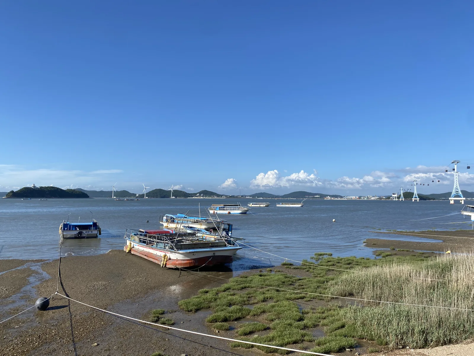 Boats resting on the tidal flats beside the beach and low islands of Jebudo in Hwaseong