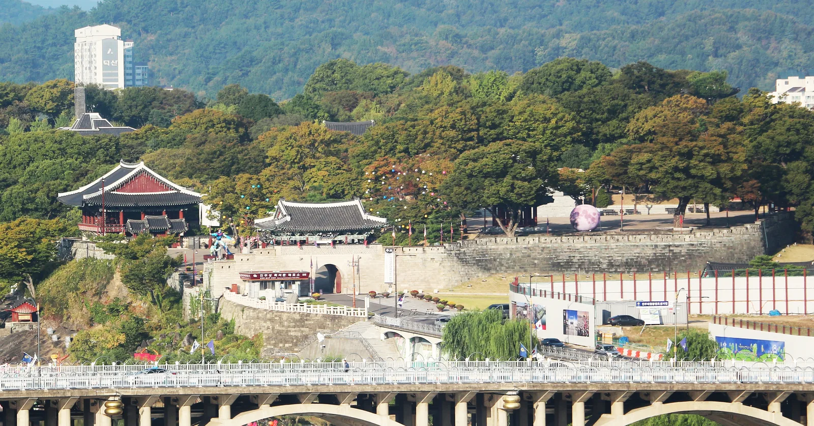 Jinju Fortress walls, traditional pavilions and tree-covered grounds seen across the Namgang River