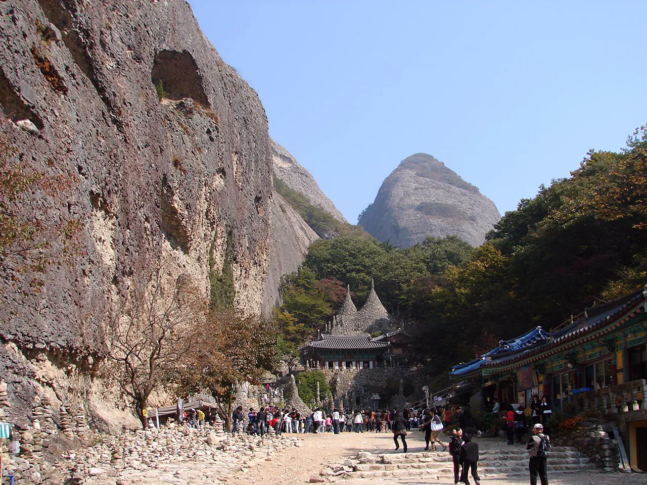 The real Tapsa Temple approach, stone pagodas and tiled roofs beneath Maisan's sheer rock walls and twin peaks