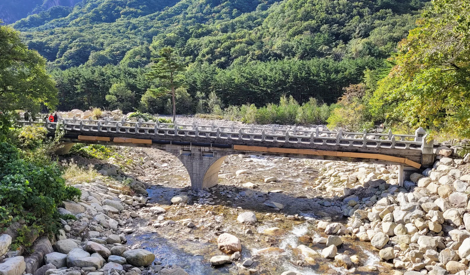 A stone footbridge crossing the rocky stream beneath forested slopes in Seoraksan National Park