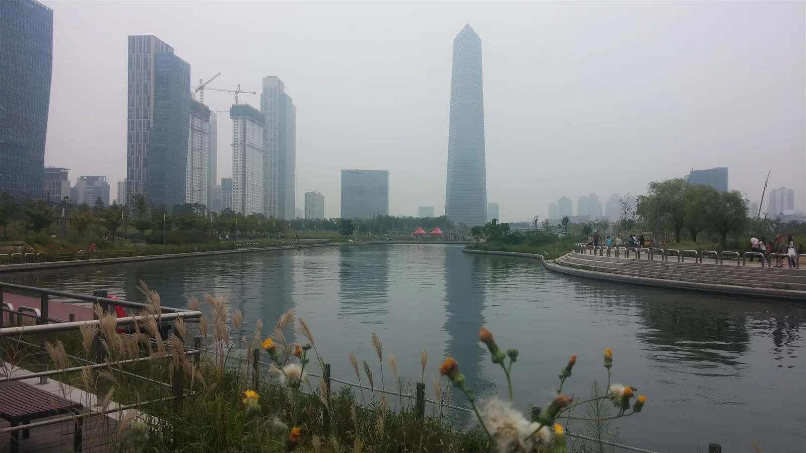 The real central canal, waterside paths, trees and modern Songdo skyline inside Songdo Central Park