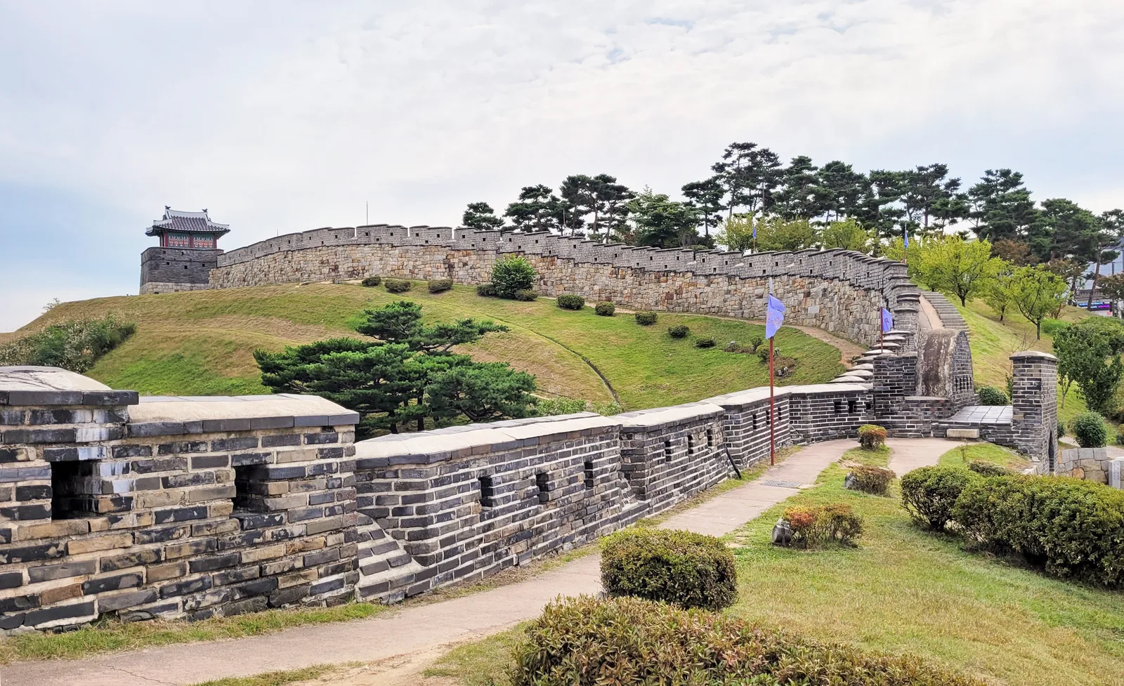 A real stone-and-brick wall sector with a painted guard pavilion and stepped ramp inside Suwon Hwaseong Fortress