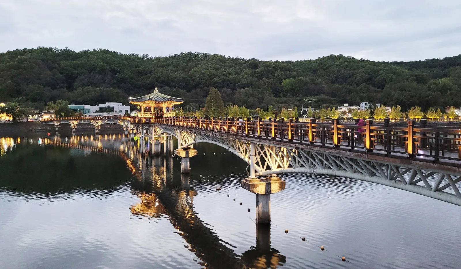 The illuminated wooden Woryeonggyo Bridge and central pavilion reflected in the Nakdong River at night