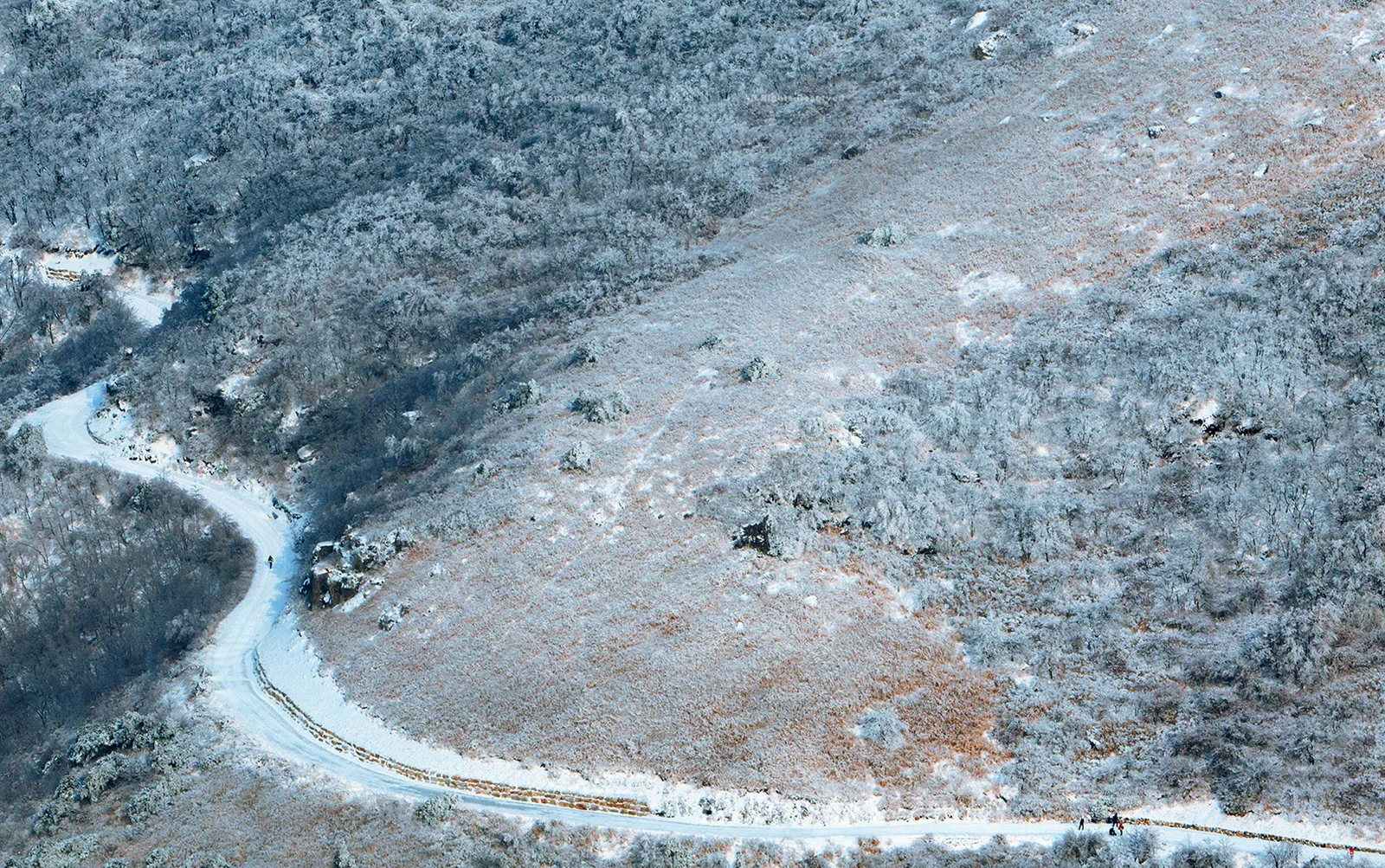 A winter aerial view of the winding mountain road and snowy slopes at Ganwoljae in the Yeongnam Alps