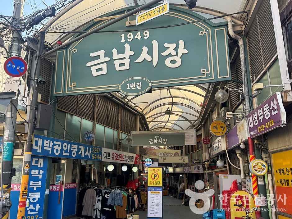 Produce and prepared-food stalls along the narrow covered lane of Geumnam Market