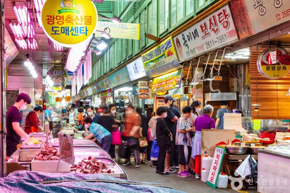 Shoppers moving between produce, seafood and prepared-food stalls inside Gwangmyeong Traditional Market