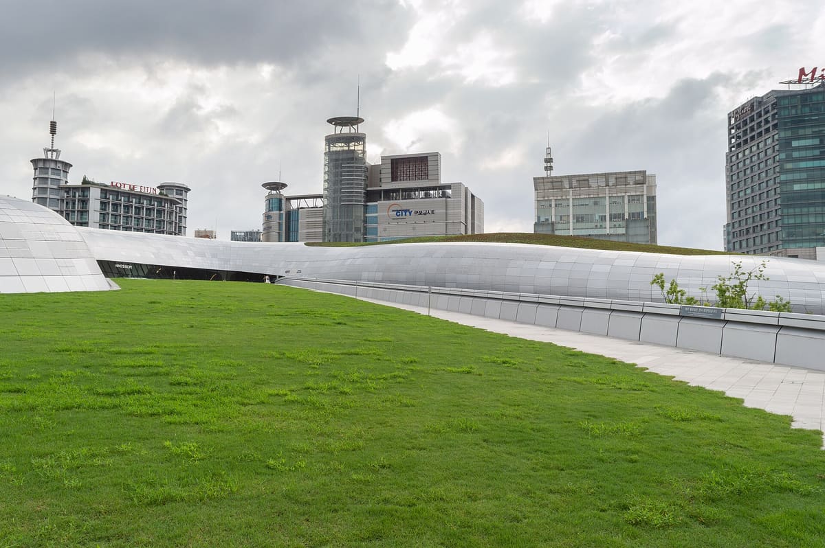The curved shell of Dongdaemun Design Plaza above its lawn