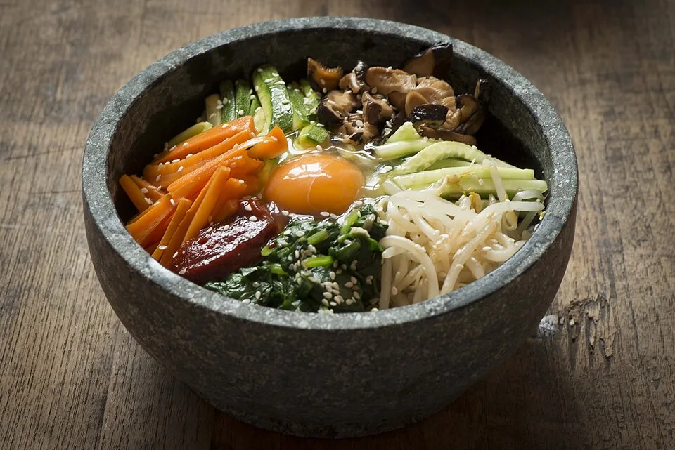 Dolsot bibimbap with rice, vegetables and an egg arranged in a hot stone bowl