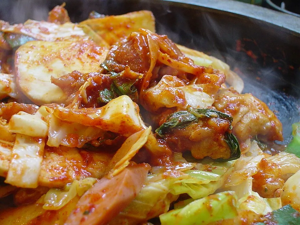 Spicy dakgalbi chicken, cabbage and rice cakes cooking together on a hot plate