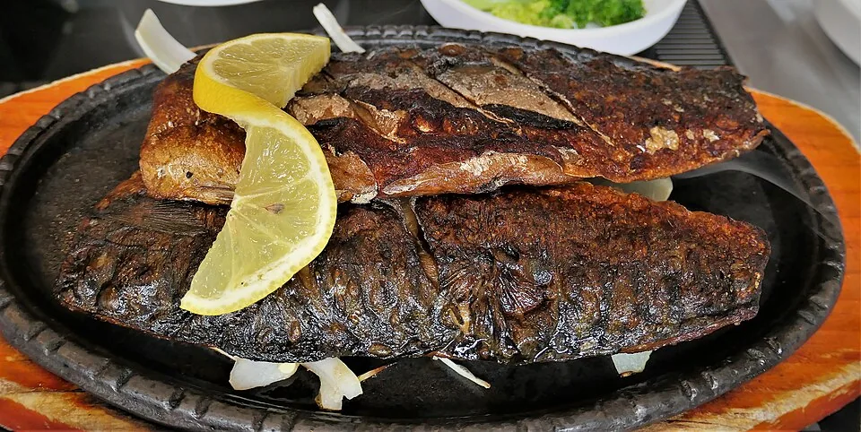 Several split mackerel fillets grilled until brown and served with lemon slices