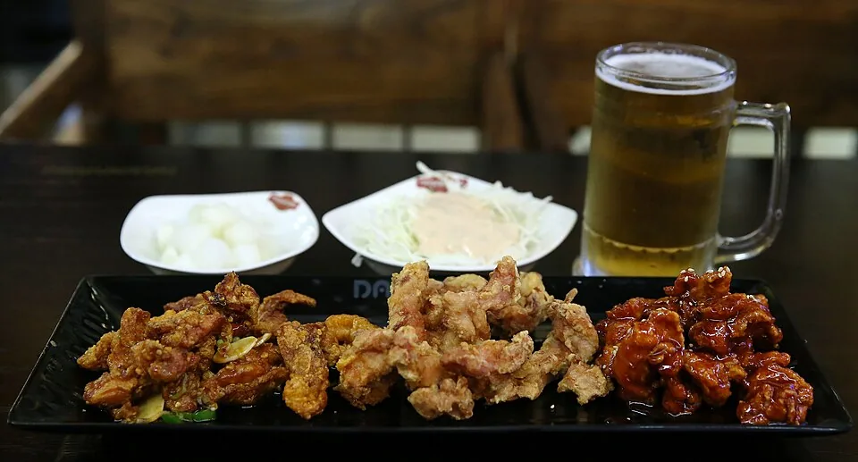 Plain and red-sauced Korean fried chicken served side by side with pickled radish