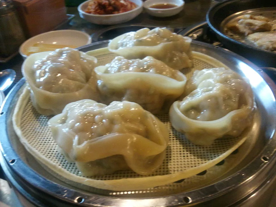 Freshly steamed Korean mandu dumplings arranged in a metal steamer basket
