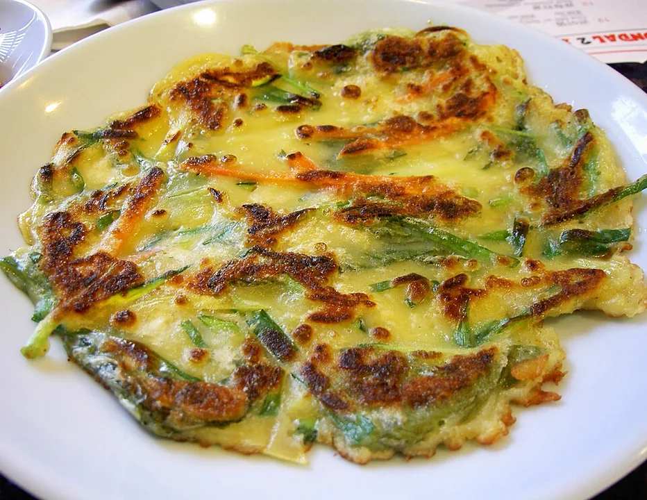A browned Korean pajeon pancake filled with long pieces of green onion