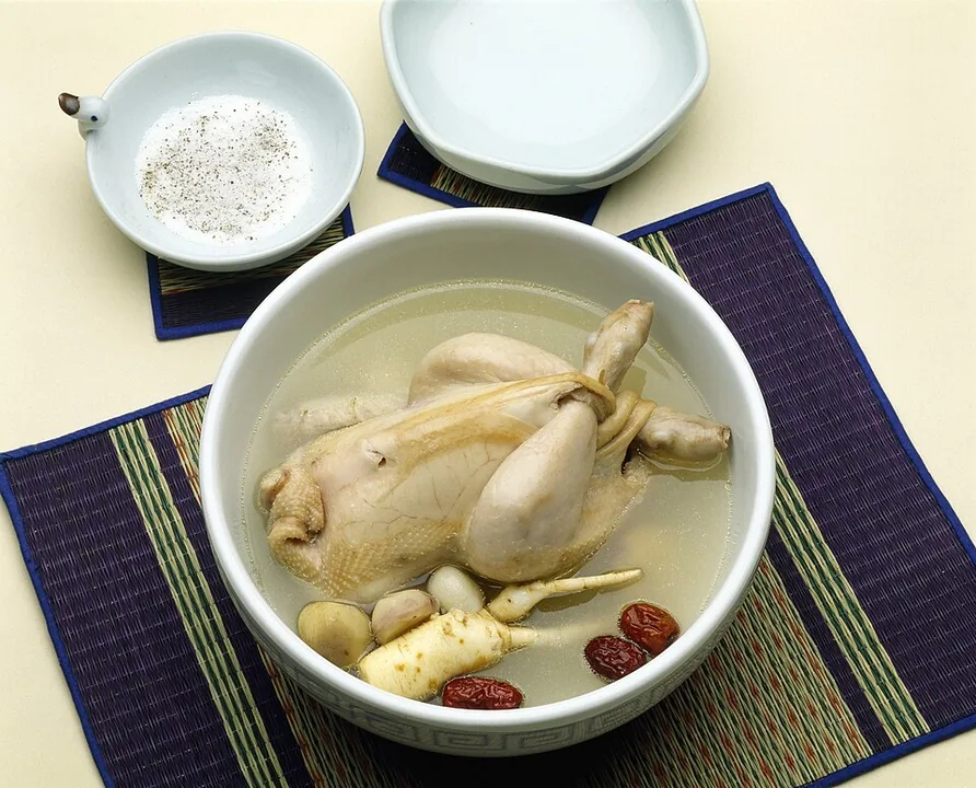 A whole chicken filled with rice and served in a bowl of samgyetang broth