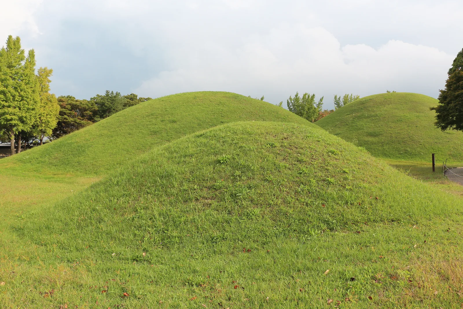 Grass-covered Silla royal burial mounds along a visitor path inside Daereungwon in Gyeongju