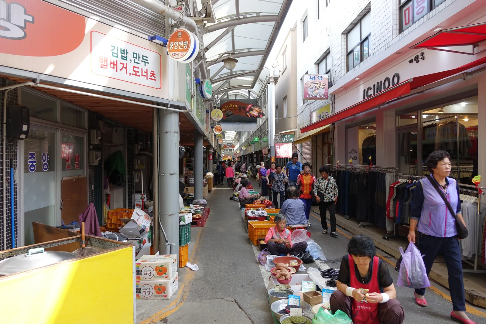 A covered aisle of produce stalls and small shops inside Gangneung Jungang Market
