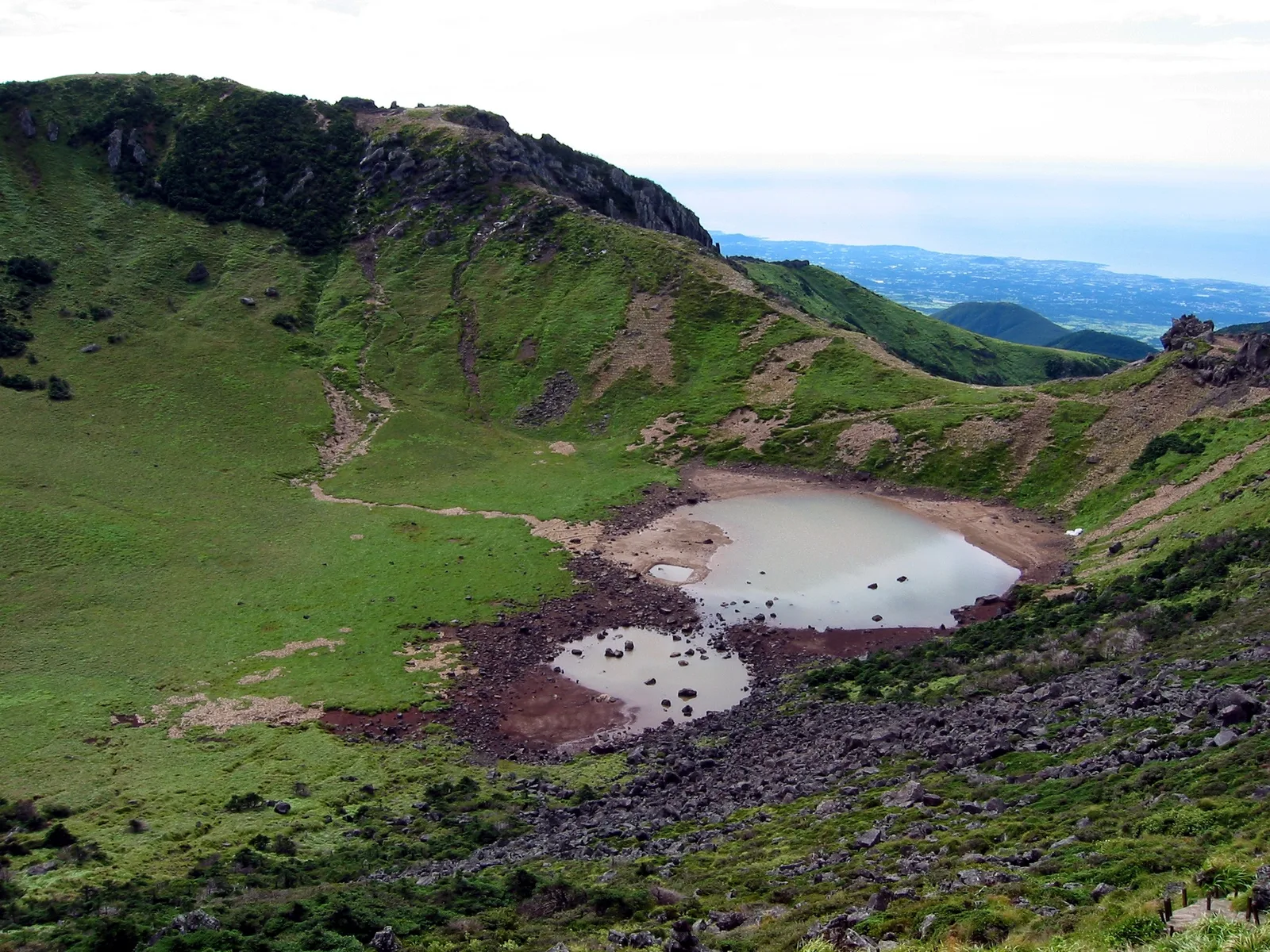 The volcanic crater rim, green slopes and hiking path around Baengnokdam at the summit of Hallasan