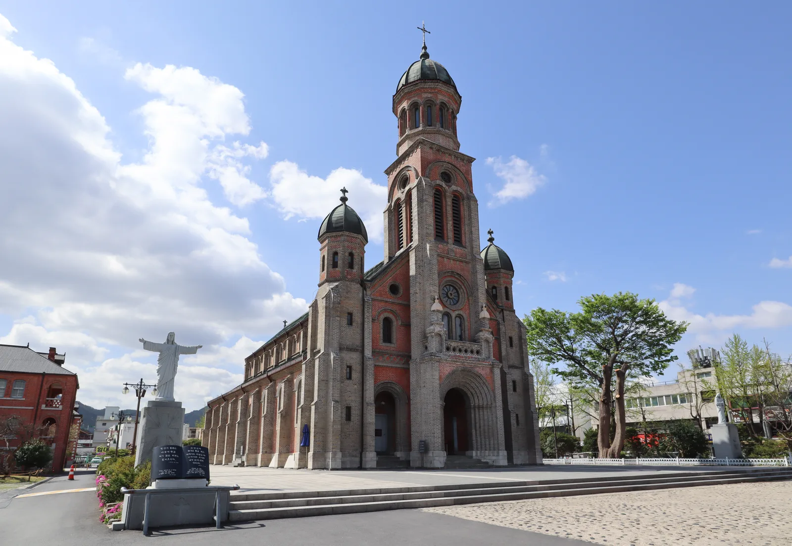 The red-brick Romanesque facade, bell towers and public forecourt of Jeondong Cathedral in Jeonju