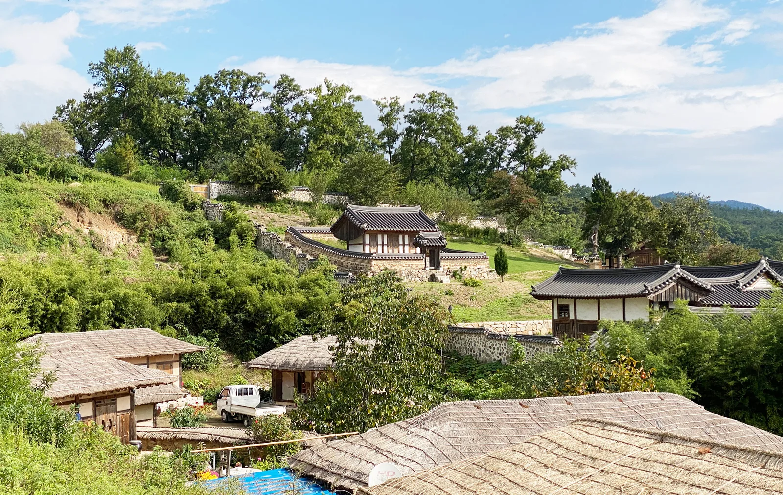 Traditional tiled and thatched houses spread across the green hillside of Yangdong Folk Village in Gyeongju