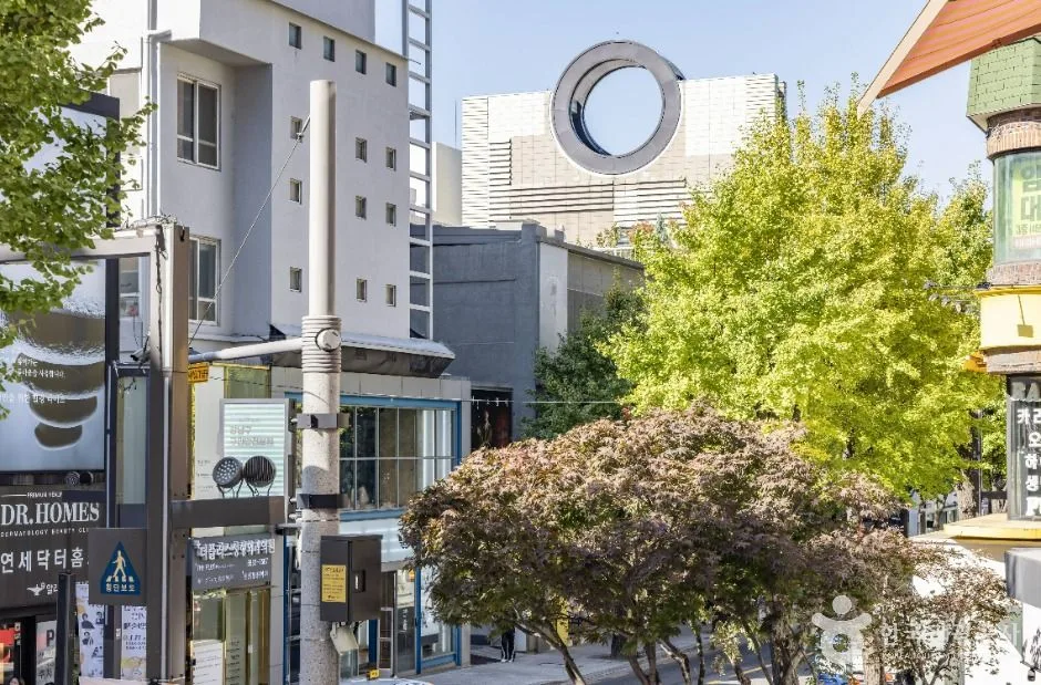 Tree-lined Garosu-gil with fashion storefronts, cafe signs and pedestrians in Gangnam's Sinsa district
