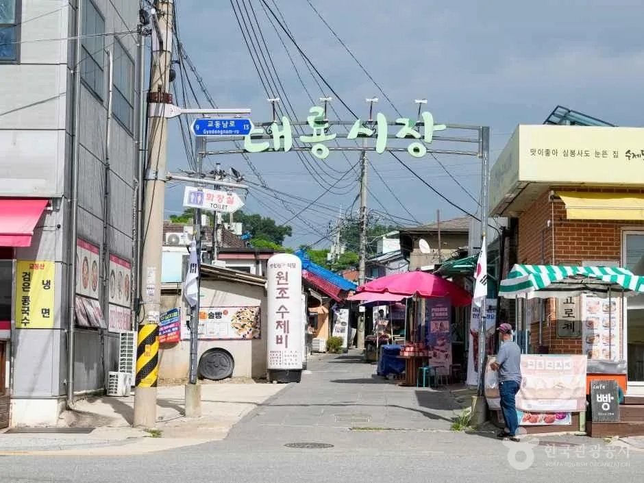 The signed entrance lane, market stalls and visitors at Daeryong Market on Gyodongdo Island