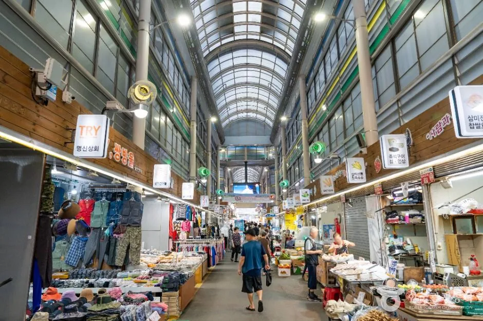Shoppers walking through the bright covered produce and food arcade inside Sammi Market in Siheung